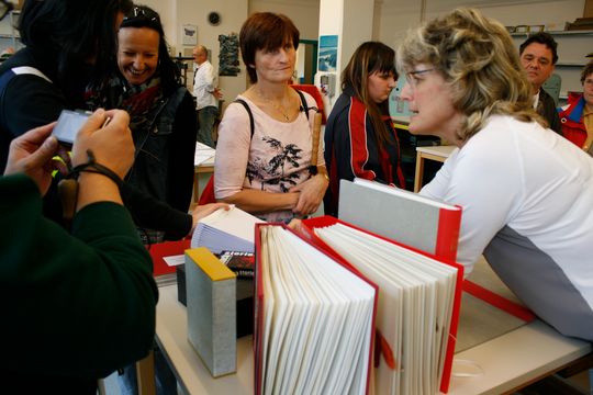 Buchbinderin erklärt einer Gruppe von Personen, wie ein Buch gebunden wird