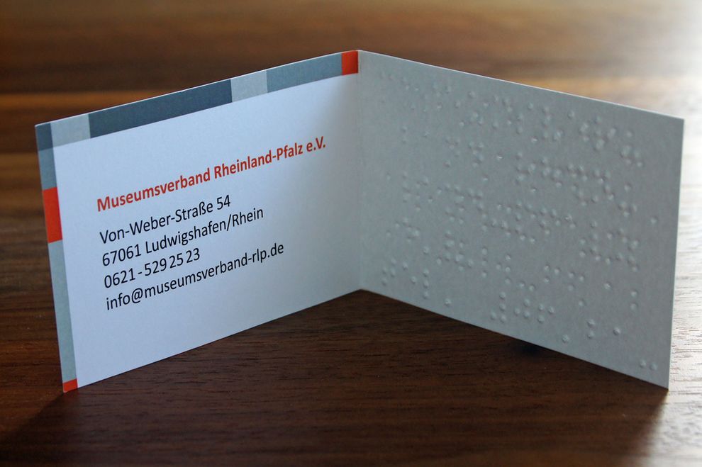 Stehende aufgeklappte Visitenkarte mit Brailleprägung und Schwarzdruck