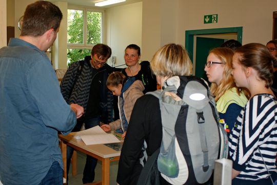 Ein Gruppe von Menschen hören den Ausführungen eines Mannes zu