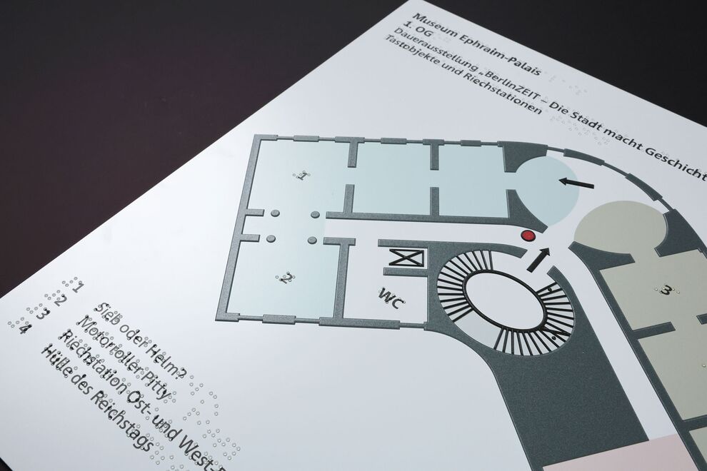 Ausschnitt aus taktilem Orientierungsplan (1. Geschoss) mit Legende (Brailleschrift/Braillelack und Schwarzdruck)