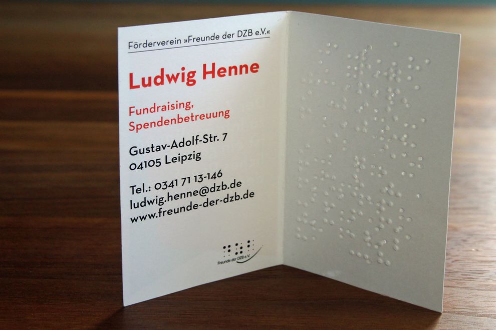 stehende aufgeklappte Visitenkarte (Förderverein dzb lesen) mit Brailleprägung und Schwarzdruck
