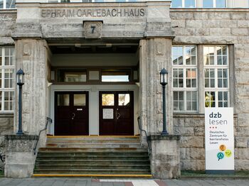 Eingangsportal mit Treppe und Firmenschild rechts