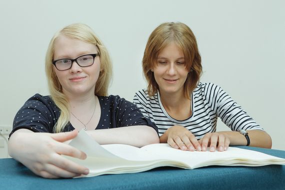 Zwei Mädchen lesen in einem Brailleschrift-Heft