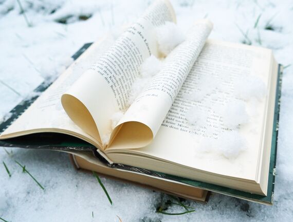 Ein aufgeschlagenes Buch mit Schnee auf einer eingeschneiten Wiese