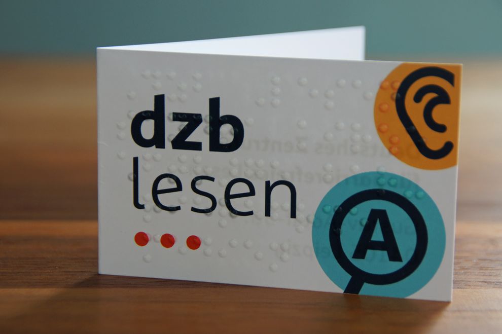 stehende aufklappbare Visitenkarte mit Braillelack und Logo dzb lesen (Vorderseite)