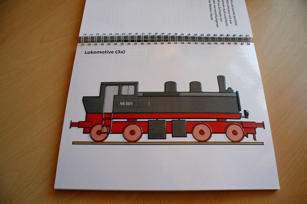 Broschüre aufgeschlagen, Relief Lokomotive