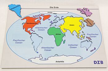 Kunststoffplatte mit Kontinenten als Puzzle-Teile, einige liegen außerhalb der Platte