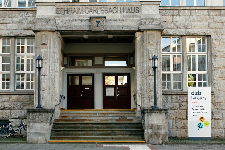 Eingangsportal mit Treppe und Firmenschild rechts